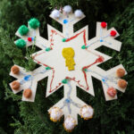 Ornament in the shape of a snowflake, decorated with mini pom poms.